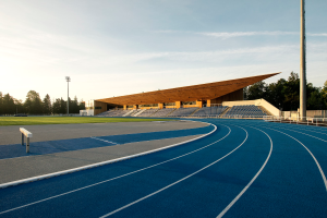 Eine blaue Laufbahn an der University of California, Berkeley, mit einer hölzernen Konstruktion in der Mitte, umgeben von Gras, Pfählen, Lampen und Bäumen, unter einem bewölkten Himmel.