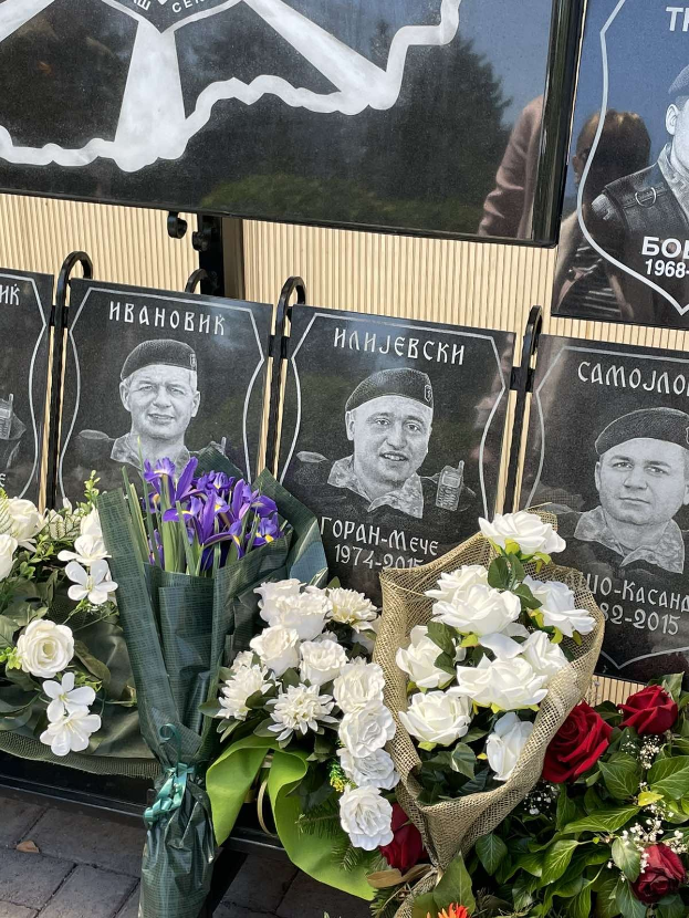 Denkmal für sowjetische Kriegsopfer mit einem farbenfrohen Blumenstrauß auf einem Bürgersteig und Gedenktafeln an der Wand.