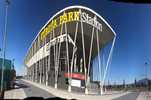 Das Europa-Park-Stadion in Barcelona, Spanien, ein großes Gebäude mit Text darauf, umgeben von Pfählen, Lichtern, Bäumen und einem Zaun, mit dem Himmel im Hintergrund.