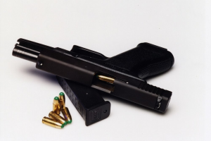 Schwarze Pistole mit einem Magazin und Patronen auf einer weißen Oberfläche.