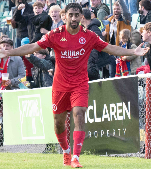 Ein Fußballspieler in roter Uniform rennt mit ausgebreiteten Armen auf einem Feld, im Hintergrund ist eine Menschenmenge zu sehen und im Vordergrund eine Tafel mit der Aufschrift "Middlesbrough FC vs. Swansea City - Sky Bet Championship".