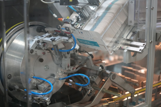 Automatisierte Verpackungsmaschine auf einem Fabriktisch mit leicht unscharfen Hintergrundobjekten.