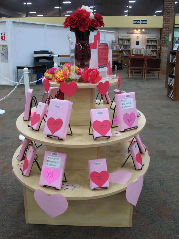 Ein Tisch mit einer Vase, Blumen und einigen Karten, mit Metallstangen, einer Maschine und Büchern im Hintergrund.