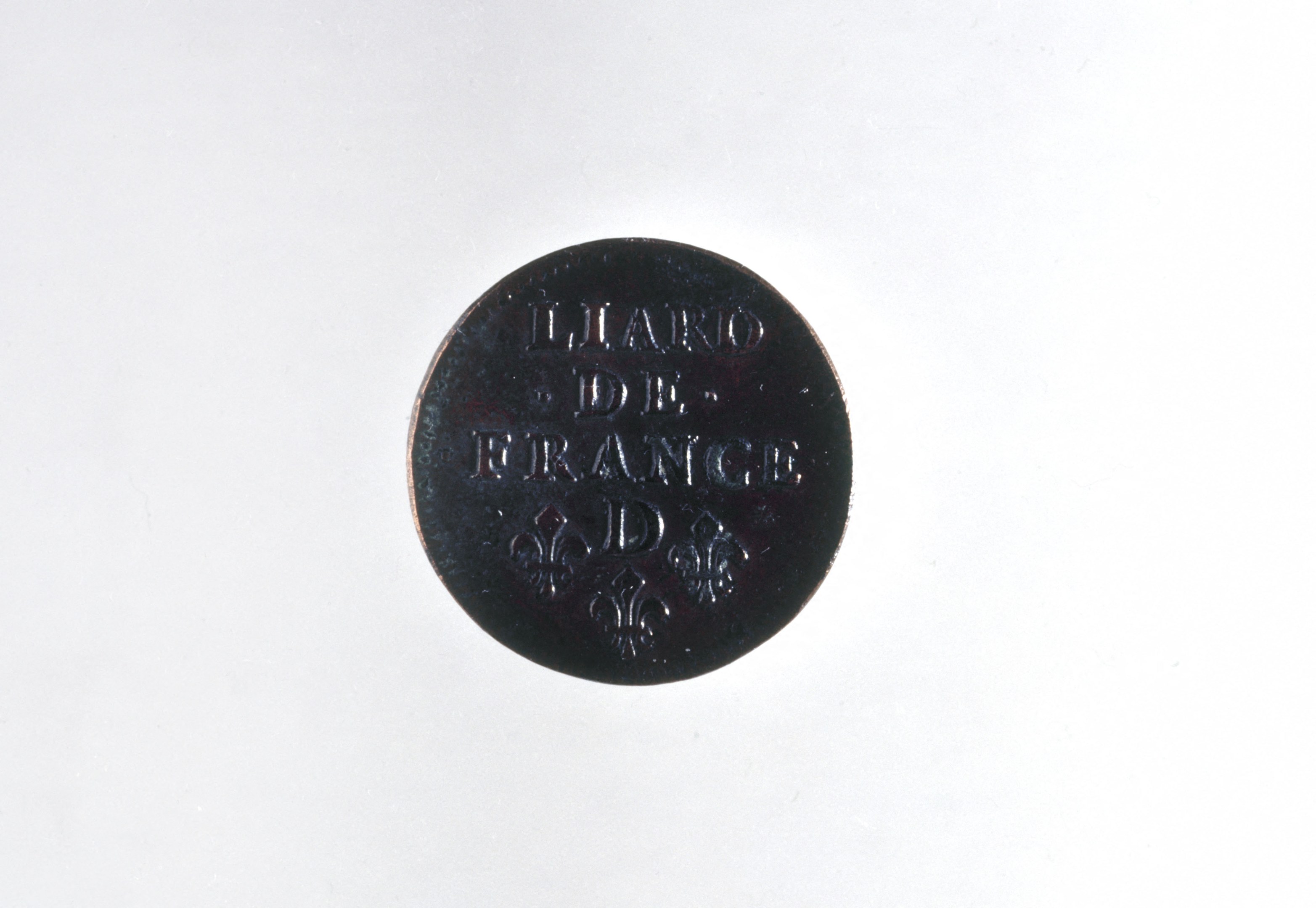 Schwarze Münze mit dem Text "Lügner de France" auf einem weißen Hintergrund.