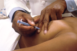 Ein Arzt in einem weißen Kittel verpasst einem Patienten auf einer weißen Fläche eine Spritze.