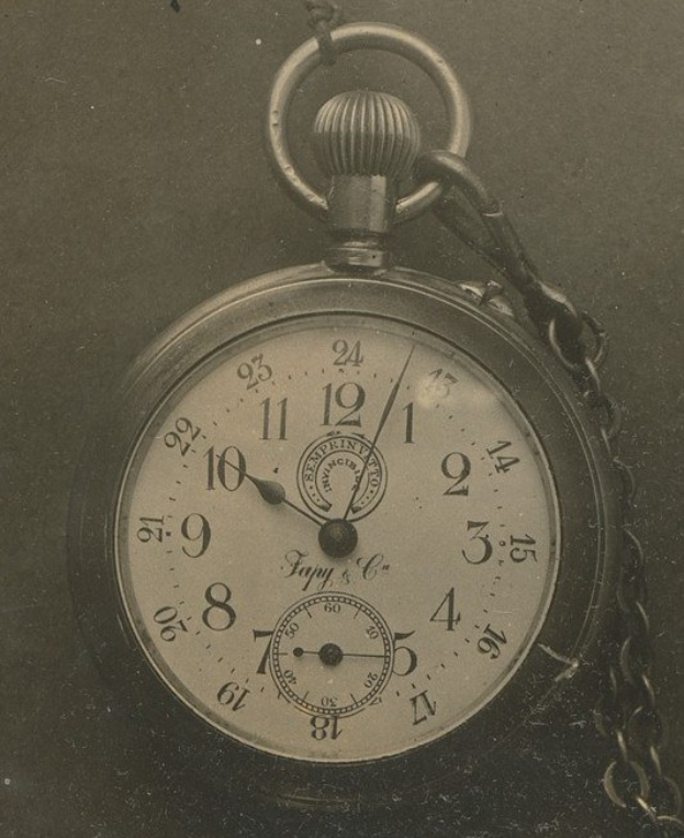 Altes Schwarz-Weiß-Foto einer Taschenuhr mit einer Kette, mit einem nummerierten Zifferblatt.