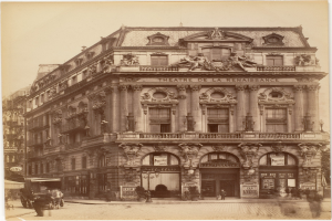 Altes Foto des Théâtre de la Renaissance in Paris mit einer Fassade mit Fenstern, Säulen, Bögen und Skulpturen, mit Menschen und Fahrzeugen auf der Straße darunter und dem Himmel im Hintergrund.