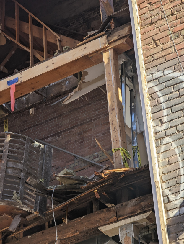 Ein teilweise abgeräumtes Gebäude mit verstreuten Holzplanken und Trömmern, zerbrochene Fenster und Türen.