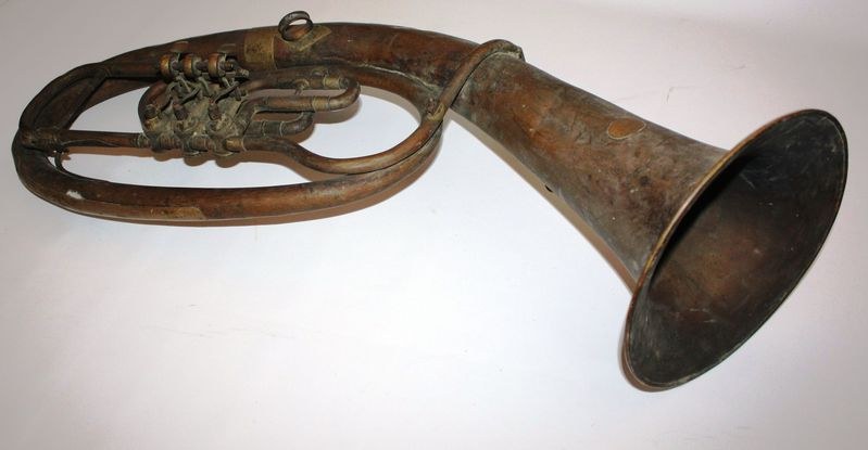 Alter Messinghorn mit glänzendem Finish, gebogenem Hals und aufgeblähtem Schalltrichter, verziert mit kunstvollen Gravuren auf einem weißen Hintergrund.