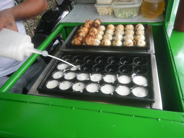 Ein Mann gießt Milch aus einer Flasche in eine Schale mit Essen auf einem grünen Tisch.
