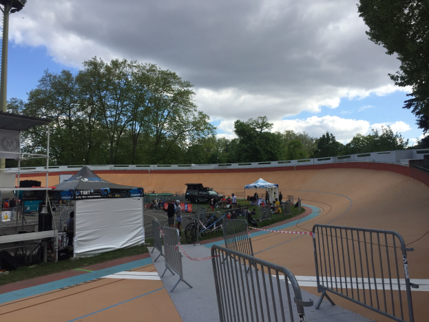 Eine Gruppe von Radfahrern auf einer Schotterstrecke bei den UCI BMX-Weltmeisterschaften 2018, mit Zuschauern, Zelten und Fahrzeugen im Hintergrund.