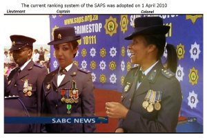 Eine Gruppe von Menschen in Uniformen und Hüten steht vor einer Banner mit Text oben und unten, der lautet "Das aktuelle Ranking-System der SAP wurde am 1. April 2010 eingeführt."