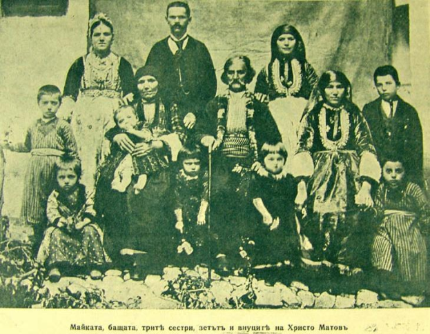 Schwarz-weiß-Foto einer Familie, die vor einem Vorhang an der Wand posiert, beschriftet mit "Russische Familie in den frühen 1900er Jahren"