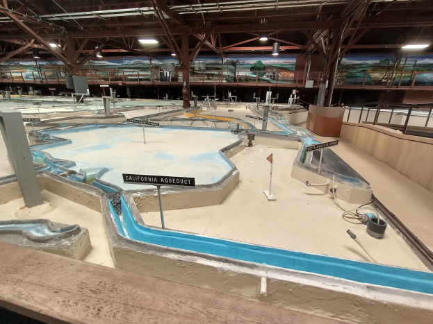 Indoor-Spielplatz mit mehreren Rutschen, Stangen, beleuchteter Decke, Wandgemälde und einem Minigolfplatz.