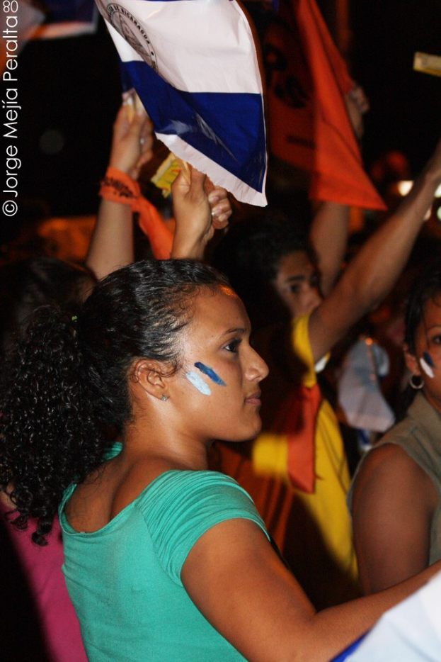 Frauen in grünen T-Shirts mit weißen Schildern, die auf einer Demonstration mit vielen anderen Mädchen im Hintergrund stehen.