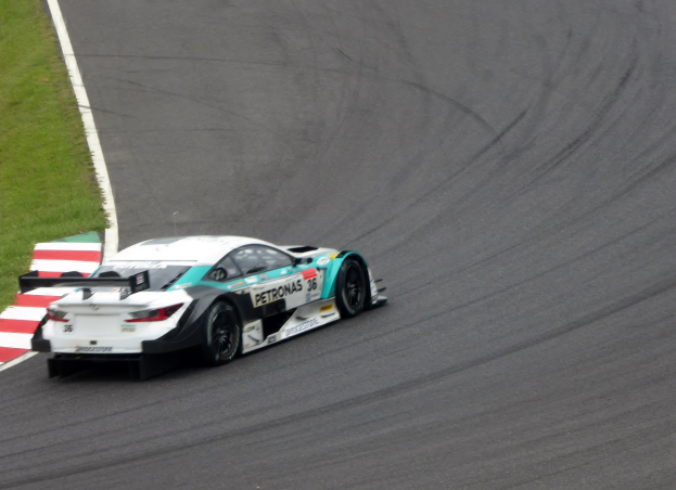 Ein silberner Mercedes-AMG GT3 Rennauto auf einer Rennstrecke mit Text auf der Karosserie und Gras links daneben.